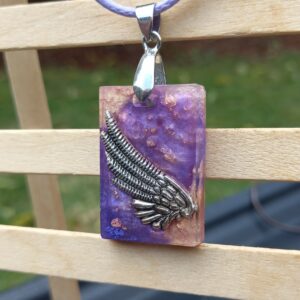 A metal wing surrounded by lavender purple and pink gold on a lilac cord necklace.