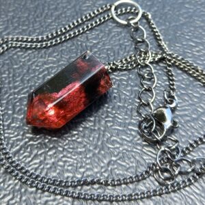 A black red resin crystal on a black chain.