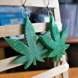 Stainless steel earrings with glittery gold emerald green cannabis leaves.
