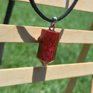 Red russet resin crystal on a black faux sued cord necklace.